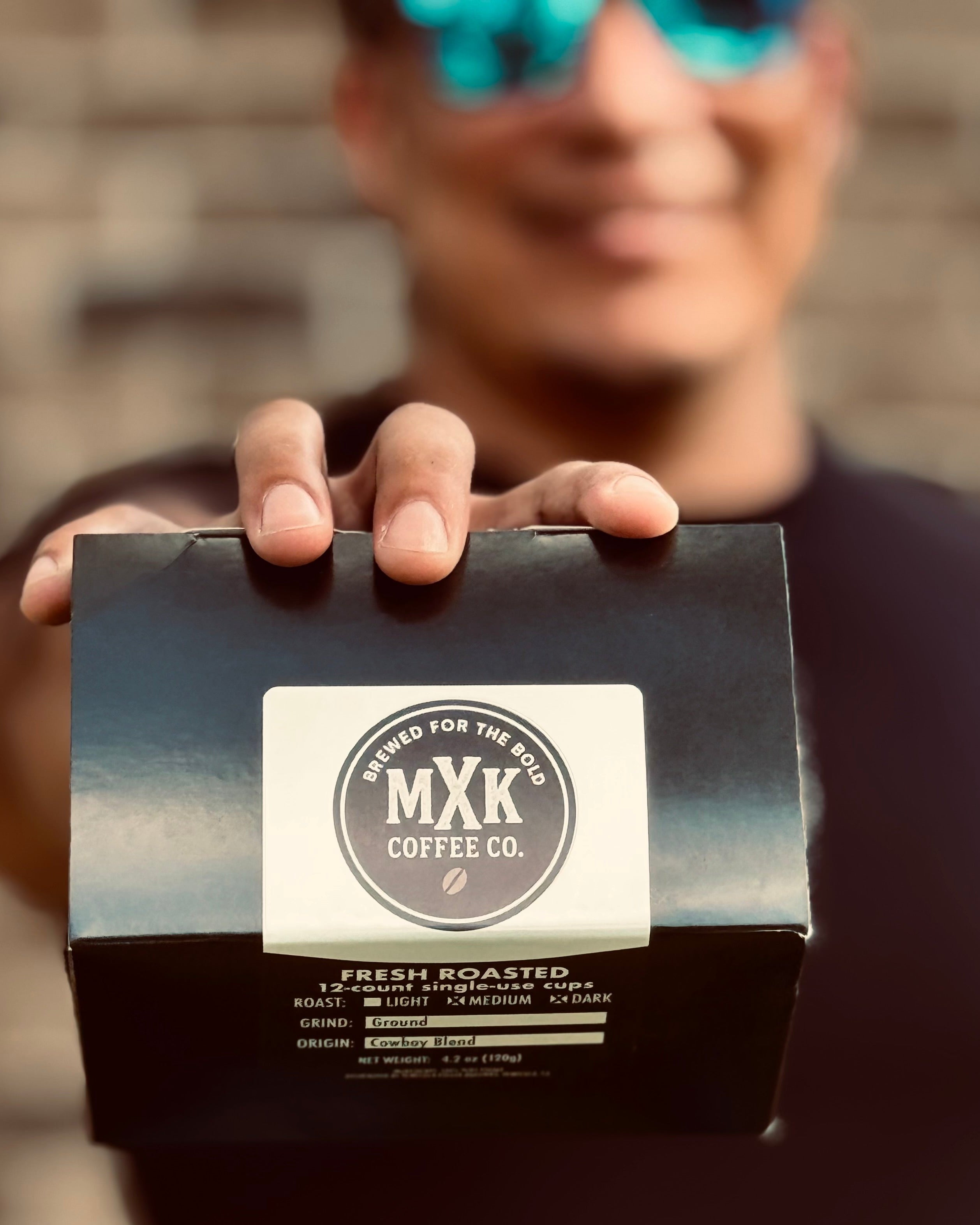 Person holding a box of MXK Coffee Co. with a blurred background